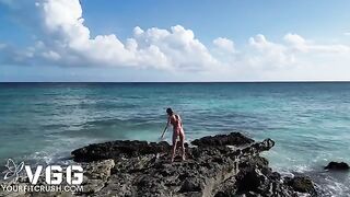 A fit petite girl is playing on the naked beach, showcasing her sexy body