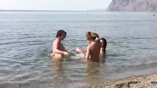 Three naked girls on the beach with a crest each, completely exposed
