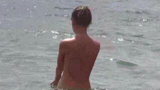 A group of naked beauties sunbathes on the sandy beach