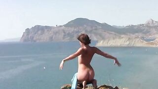 A girl is sunbathing naked on the beach and playing with her pussy