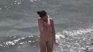 Nudist couple enjoy each other on the beach with no clothes on