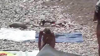 Nudist couple enjoy each other on the beach with no clothes on