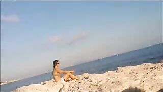 A young girl is basking in the sun naked on the beach