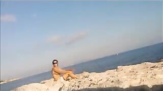 A young girl is basking in the sun naked on the beach
