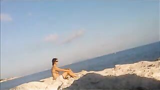 A young girl is basking in the sun naked on the beach