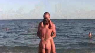 A group of naked gymnasts are doing acrobatic exercises on the beach